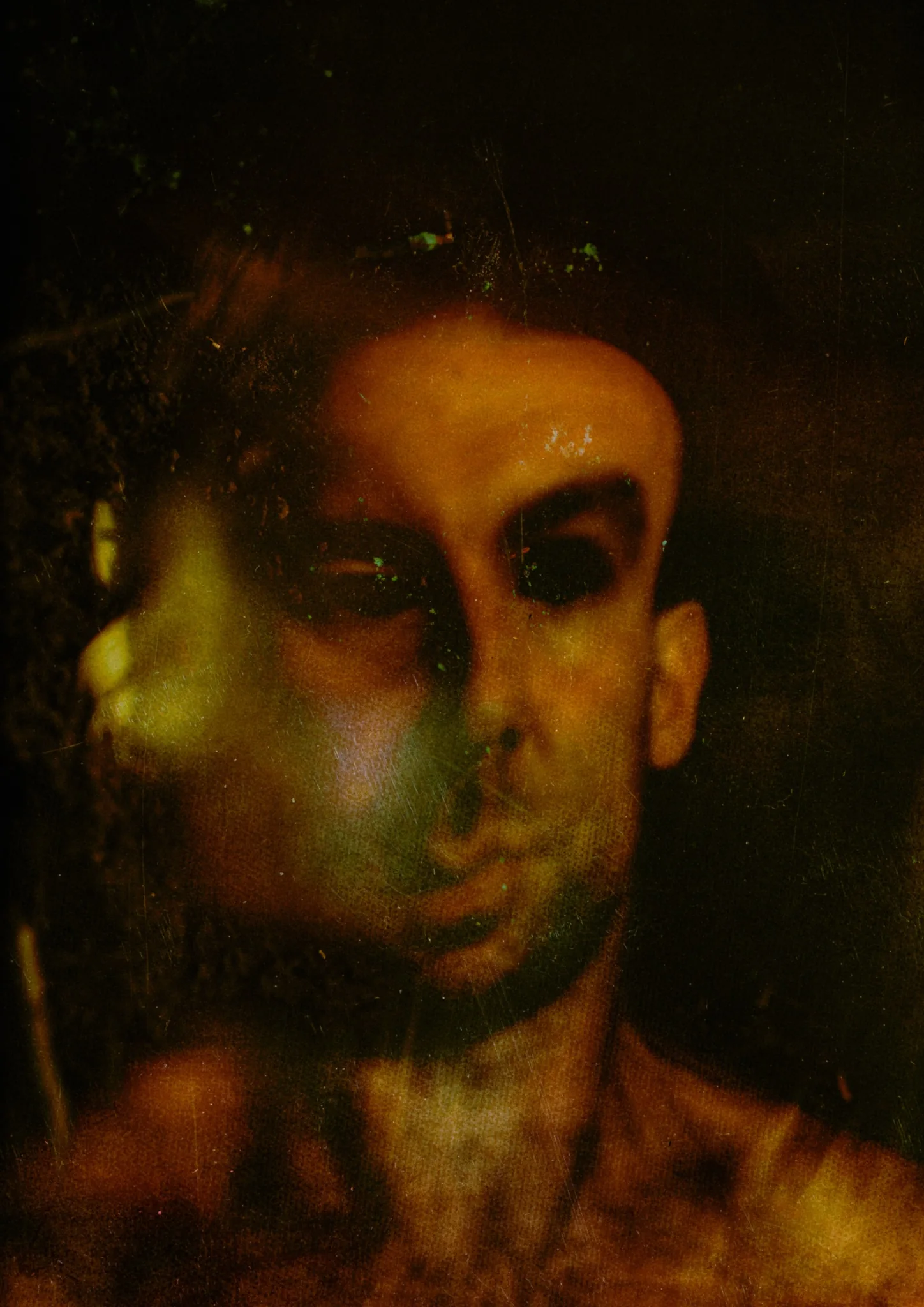 Layered self-portrait in deep amber, olive and black, with scratched photographic surfaces.